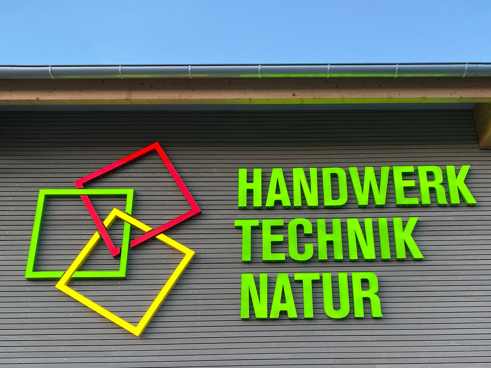 Leuchtreklame „Handwerk Technik Natur“ an einer Fassade
