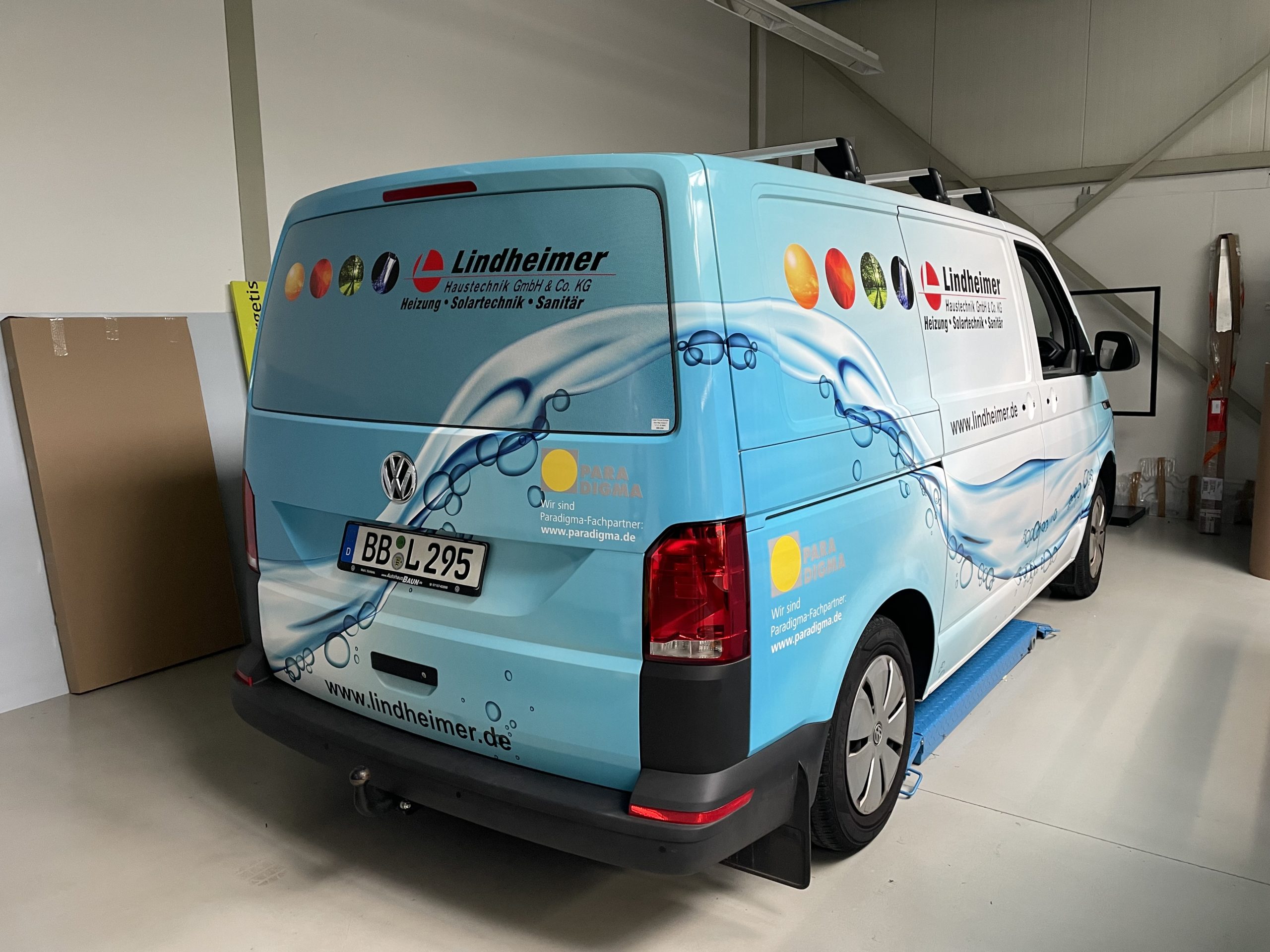 Hellblauer Transporter mit Wasser-Motiv und Firmenbeschriftung