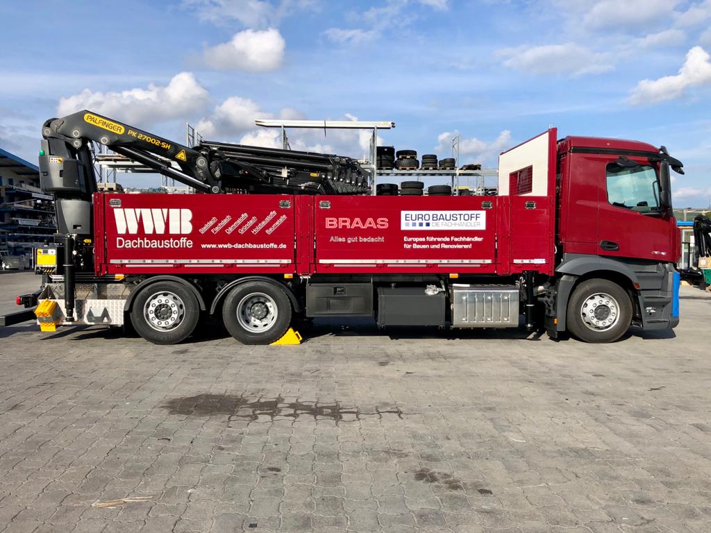 Rot beschrifteter Kran-Lkw mit BRAAS-Werbung