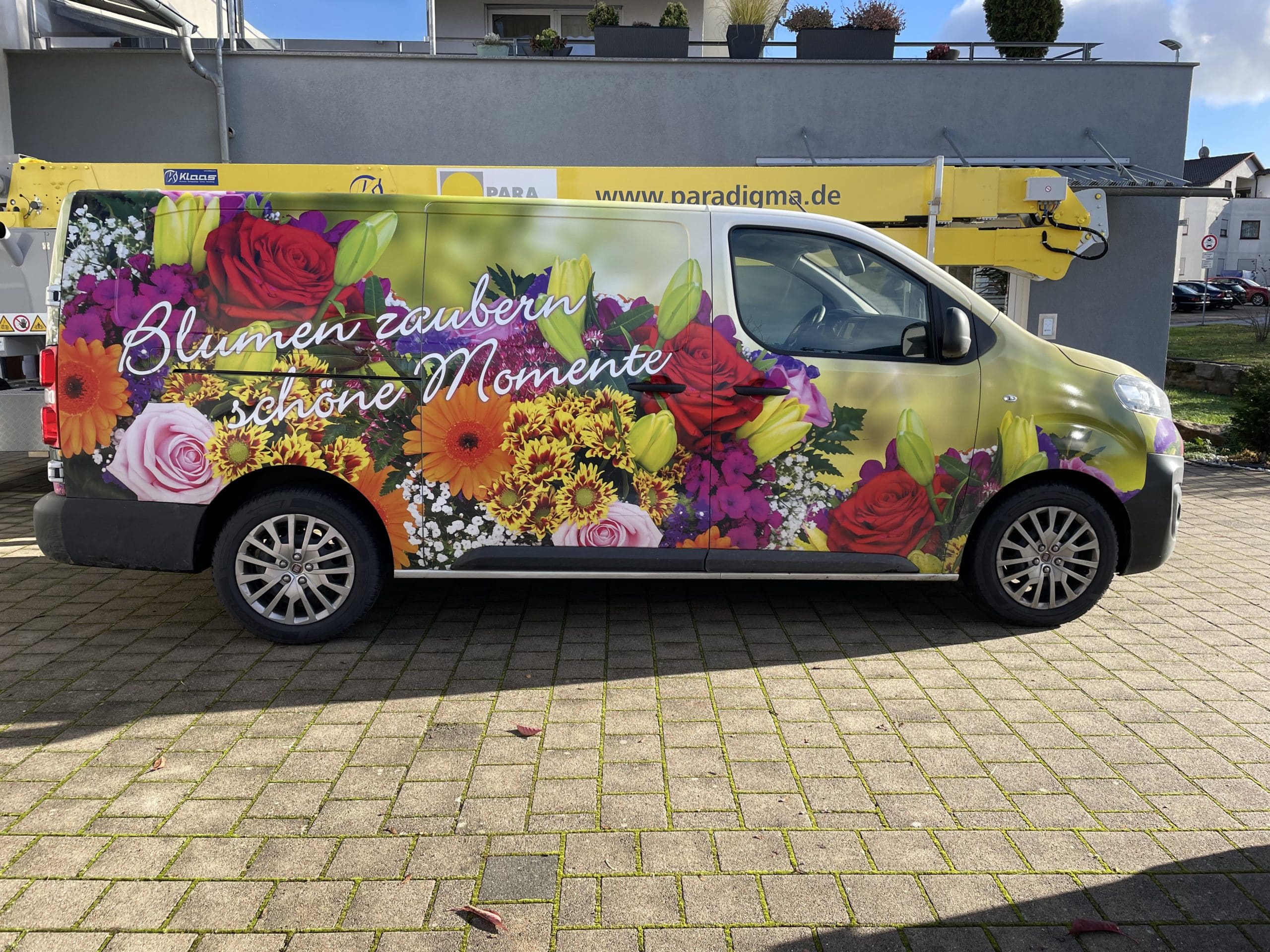Blumig folierter Transporter mit dem Werbespruch „Blumen zaubern schöne Momente“